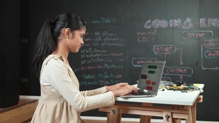 high school girl writing code or engineering prompt while attend in STEM technology class. Teenager coding or programming system while looking at computer screen in front of blackboard. Edification