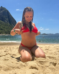  A smiling young woman with braided hair in a red bikini enjoys a bright tropical beach, captured in a relaxed and joyful summer moment.
