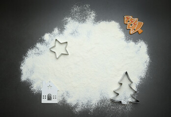 A dark Christmas background with scattered flour and cookie cutters shaped like a tree and star, creating a clean festive frame for holiday baking themes, decorative seasonal layouts, winter marketing