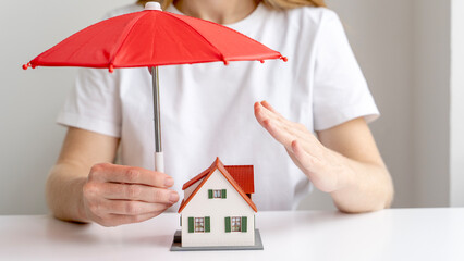 Realtor or insurance agent cutting an umbrella over a model of a house. The concept of insurance and security of housing and mortgages. Mortgage Insurance of Real Estate