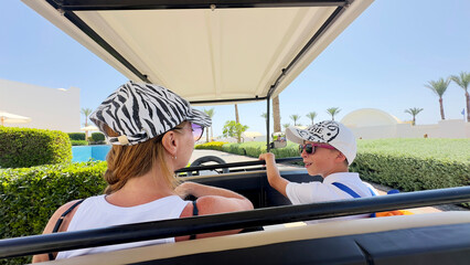 Woman with her son in an electric car on the beach by the sea