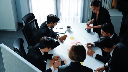 Top view of business people brainstorm idea by using sticky notes while planning marketing strategy at meeting room. Group of diverse team discuss about financial plan. Teamwork concept. Directorate.