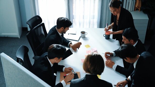 Top view of business people brainstorm idea by using sticky notes while planning marketing strategy at meeting room. Group of diverse team discuss about financial plan. Teamwork concept. Directorate.