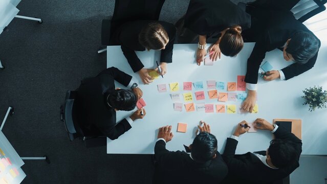 Top view of smart business team planning marketing strategy at meeting room. Professional executive manager exchange data and brainstorm idea while writing in sticky notes at workplace. Directorate. - Powered by Adobe