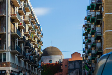 Urban Cityscape With Stacked Apartments And Dome-Shaped Building Under Clear Blue Sky