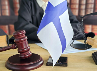 Court session in Finland with gavel, flag, and scales of justice displayed on the bench concept