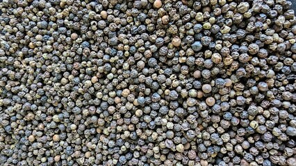 Close-up view of a large pile of dried peppercorns at a spice market