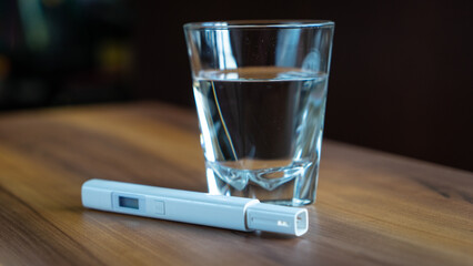 water quality tester and glass of water on the table
