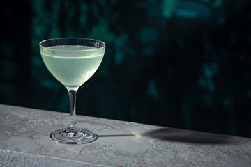 Cocktail on the table with bar wall background. Margarita sour drink placed on the counter at restaurant or night club. Refreshing classic alcoholic beverage in stylish glass. Summer terrace