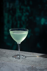 Cocktail on the table with bar wall background. Margarita sour drink placed on the counter at restaurant or night club. Refreshing classic alcoholic beverage in stylish glass. Summer terrace