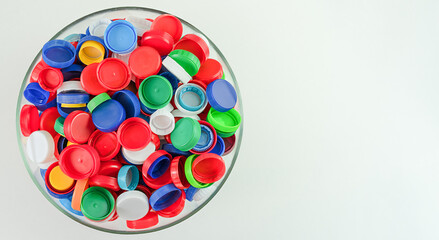 Bright plastic lids of different colors in a transparent bowl - red, blue, green, white, yellow.