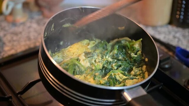 The Cooking scrambled eggs with spinach in a pan