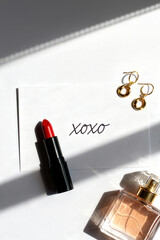 Tennis lifestyle essentials with lipstick, earrings, and perfume presented on a sunny, stylish surface