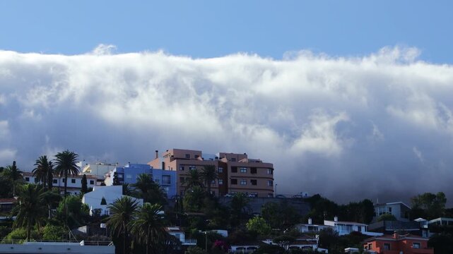 El impresionante efecto foehn, timelapse de nubes descendiendo por las cumbres en la isla de La Palma, en primer plano un poblado, video en alta resoluci&oacute;n.