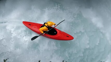 Kayaker in red boat moves through intense whitewater, entering a steep drop, steering precisely through fast currents and splashes while maintaining stable forward motion in rough rapids
