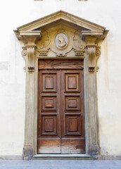 Historic Wooden Door with Ornate Stone Frame in Florence, Italy