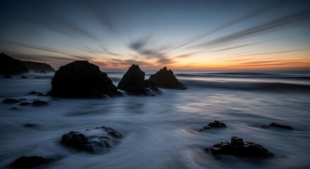 A serene coastal landscape captured with long exposure, showing the dynamic motion of streaking clouds and misty sea around silhouetted rocks at sunset