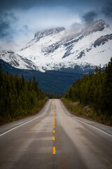 Fototapeta premium Empty mountain highway leading into snowy peaks