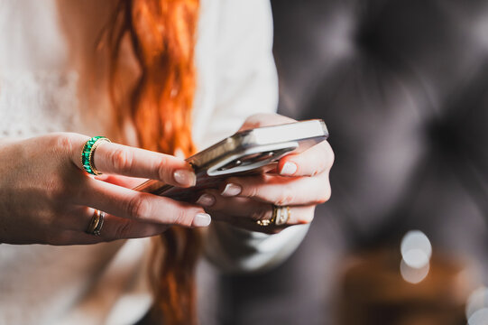 Close-up of a person's hands holding and scrolling a smartphone. The user is interacting with their mobile device, likely texting, browsing social media, or shopping online.