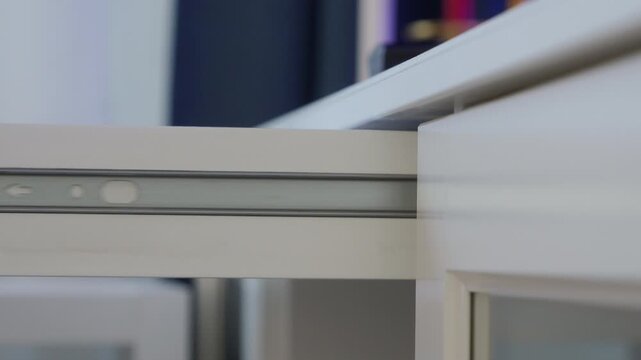 Hand holding white plastic key to open a white cabinet drawer secured by a child safety lock. The magnetic lock is activated and the drawer is pulled open.