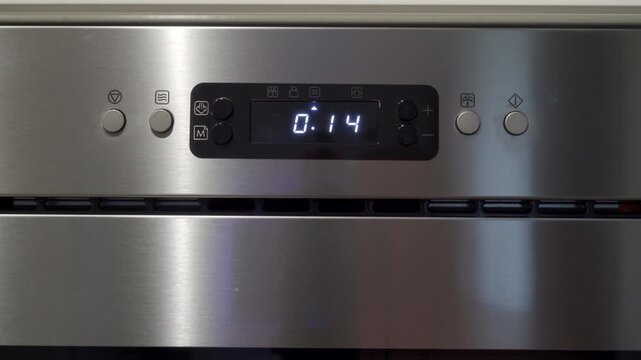 Stainless steel microwave control panel with digital display showing the time countdown. The timer reaches zero. A sharp, loud, continuous electronic beeping sound signals the end of the cooking cycle