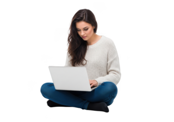 A young woman with long dark hair wearing a white sweater and blue jeans sits cross legged working on a laptop isolated on transparent background