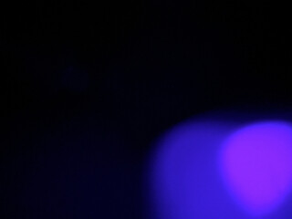 Luminous purple-magenta bokeh sphere with soft light diffusion creating mystical cool-tone glow and atmospheric bokeh effect against pure black background. Authentic film light leak showcasing creamy 
