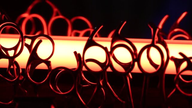 Professional barber scissors and shears stand organized in a backlit display. Dramatic lighting highlights the shiny metal tools used for precision haircutting in a modern salon or barbershop.