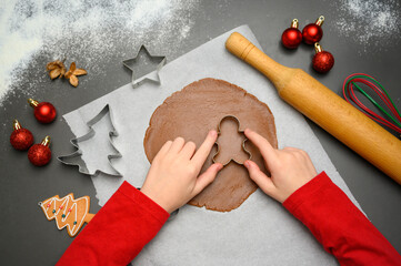 Close-up view of kids&rsquo; hands shaping gingerbread cookies with Christmas cutters on a decorated baking surface. Perfect for winter marketing, homemade baking concepts, family holiday themes