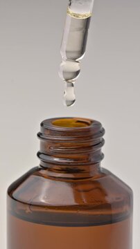 A pipette with cosmetic oil dripping into a jar