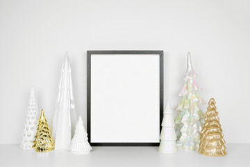 Christmas mock up with black wooden frame and gold and white Christmas tree decor. Portrait frame on a white shelf against a white wall. Copy space.