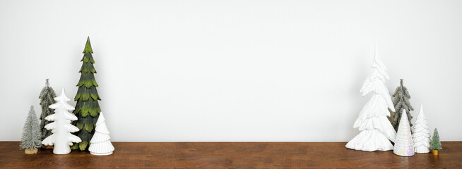 Green and white Christmas tree decor on a wood shelf against a white wall banner background with copy space
