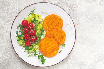 crispy fried fish cutlets, fish burgers, on a white plate, with fresh lettuce leaves, arugula and cherry tomatoes, homemade, no people,