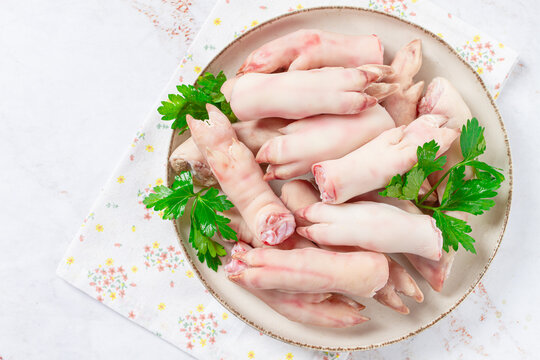 Pork trotters arranged on a plate with fresh parsley on a white background