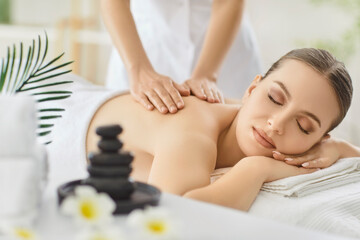 Serene woman enjoy soothing back massage with eyes closed, female masseuse hands gently press and...