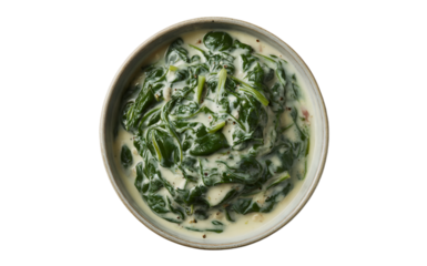 A top-down photograph of creamy spinach served in a rustic ceramic bowl against a clean white background. The spinach is rich and velvety, with deep emerald green leaves folded into a smooth, pale cre