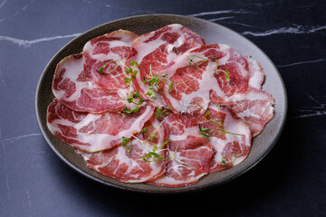 plate with sliced cured meat, pork neck, prosciutto coppa