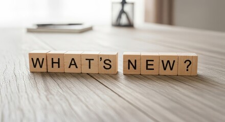 Curiosity Unveiled: Wooden blocks spell out WHAT'S NEW?, inviting curiosity and anticipation against a clean, uncluttered surface, sparking exploration and discovery.
