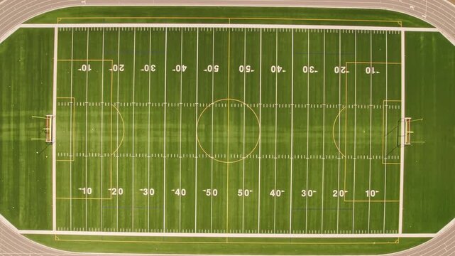 Imitation of the sport ball kicked and flying up fast. Fast speed ascending aerial top down view of empty soccer field without players. Football field with grass and white paint lines and marks.