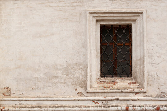 solid brick plastered wall with a barred window