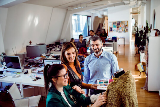 Adult coworkers smiling while collaborating on fashion design in modern studio