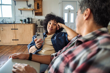 Adult couple having a thoughtful smartphone chat at home