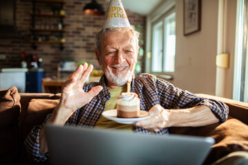 Senior man happily celebrating birthday on video call at home