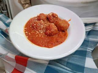 Polpette al sugo con parmigiano grattugiato su piatto bianco 210