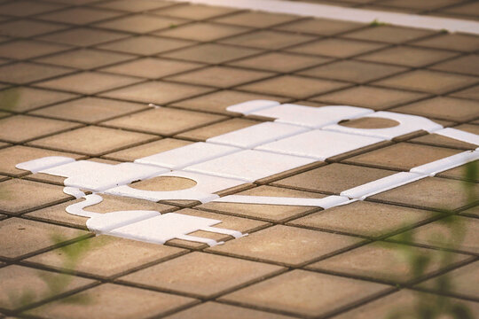 Electric vehicle parking marking on paved charging station site in clear daylight with modern chargers in the background.