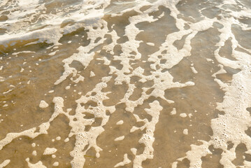 Sea foam patterns on shallow beach water