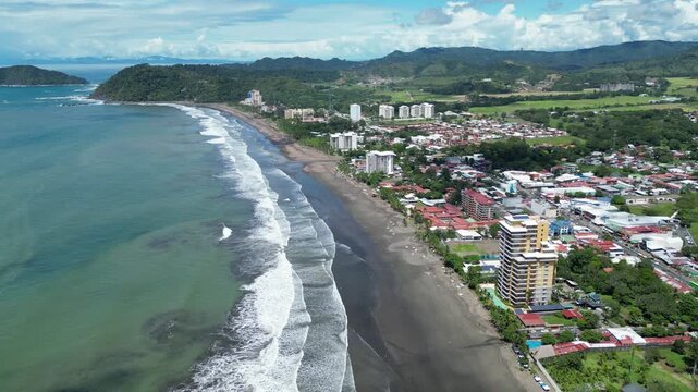 Aerial view of the beach town of Jaco with tourist and hotel buildings and businesses with vegetation in the background on a warm morning. Jaco Beach, province of Puntarenas in Costa Rica