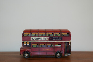 Obraz premium Bucharest Romania 16 November 2025.A vintage painting of a classic red English bus displayed on a wooden table. The artwork features the iconic double-decker bus in retro tones.