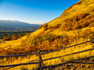 Golden sunrise light over Ensign Peak slopes overlooking Salt Lake City and distant mountains