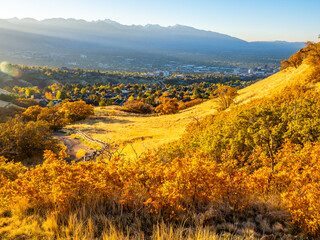 Golden sunrise light over Ensign Peak slopes overlooking Salt Lake City and distant mountains